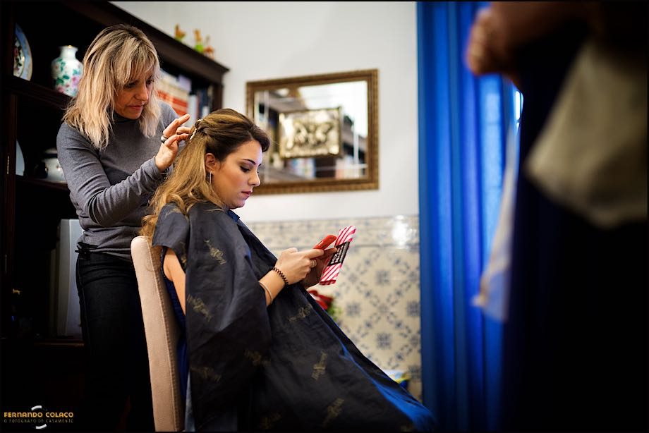 A friend of the bride, sitting in a chair, getting her hair done for her wedding.