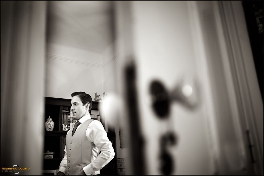 Seen through a poorly closed, out-of-focus door, the groom wears his wedding suit vest.