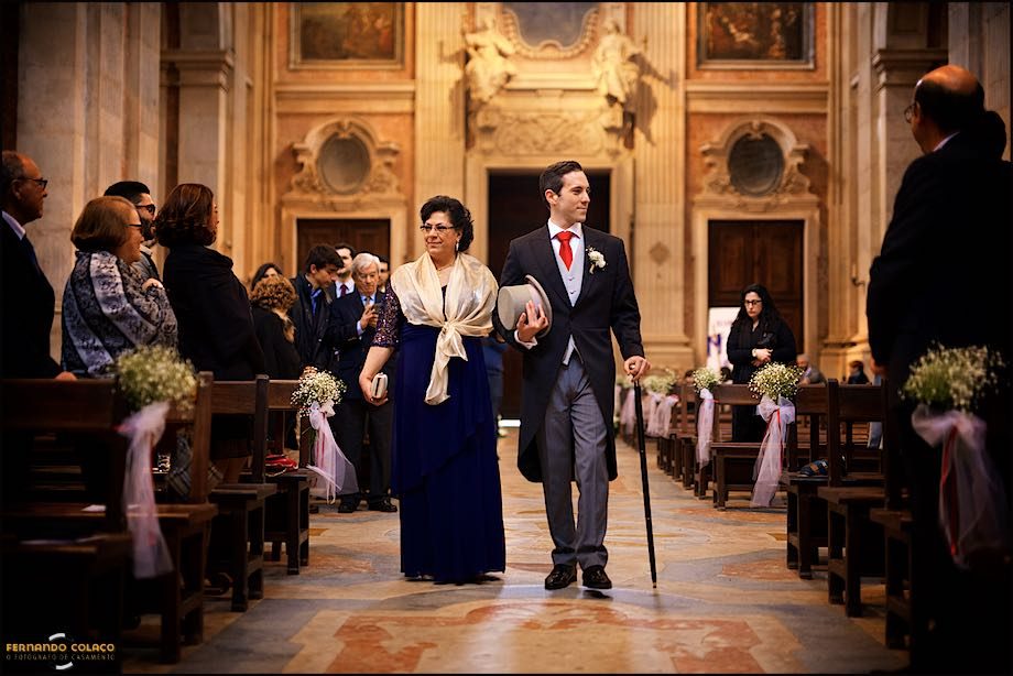 Inside the Basilica of Mafra, the groom with his mother walk through the wing, among the guests, to the altar.