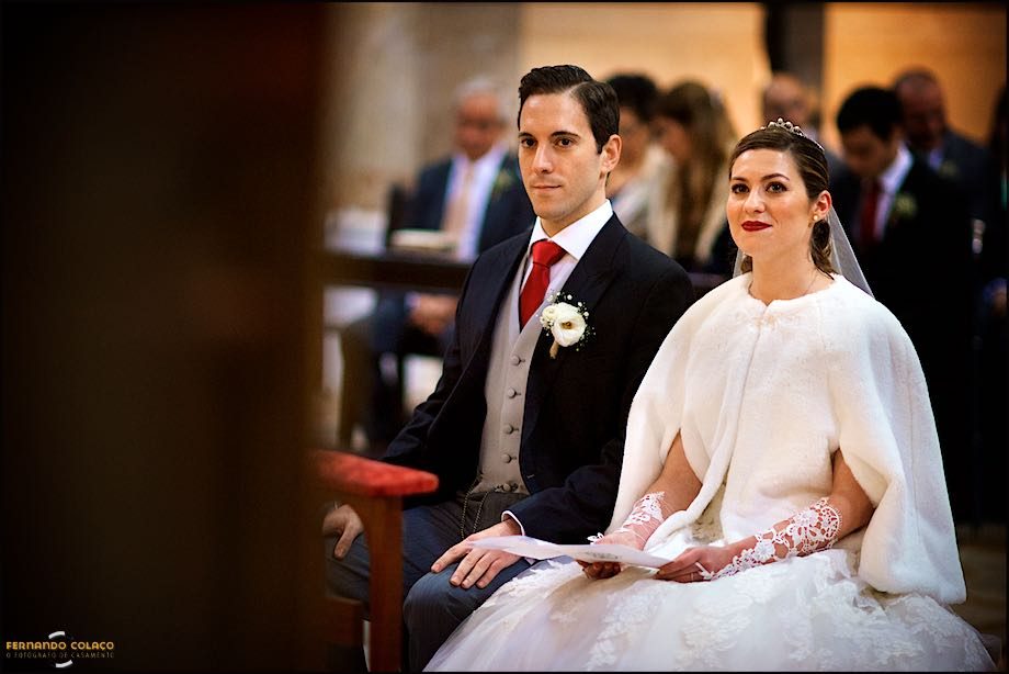 The couple sitting in front of the altar of the Basilica of Mafra, as part of the wedding ceremony.