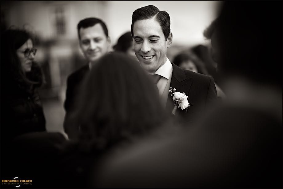 Among guests congratulating him on the wedding, the groom smiles at a guest.