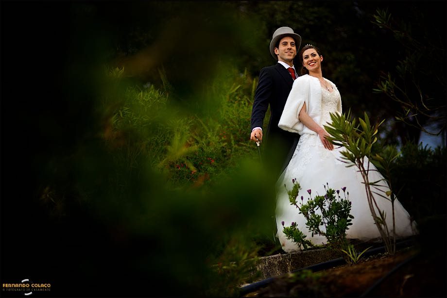 In the session with the wedding photographer, the bride and groom pose together, standing amidst the plants in the garden of Casa de Reguengos.