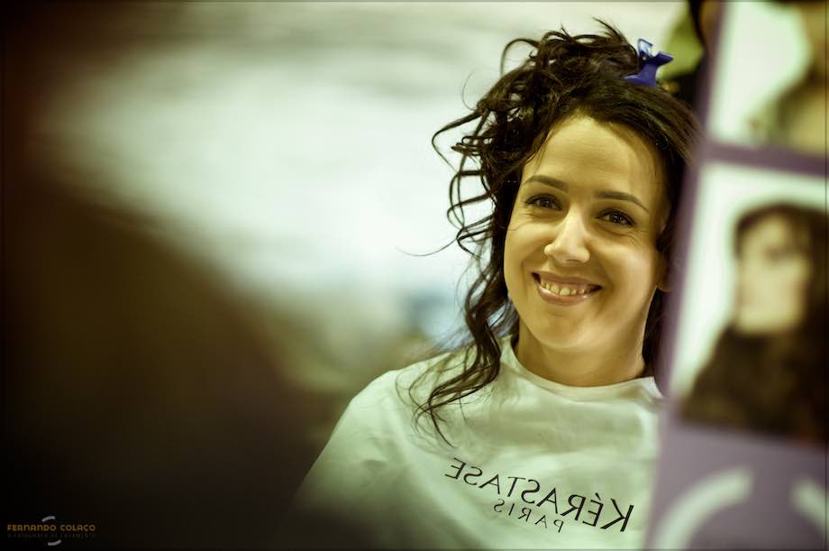 Seen in a mirror at the hairdresser's, the bride smiles with her hair all disheveled.