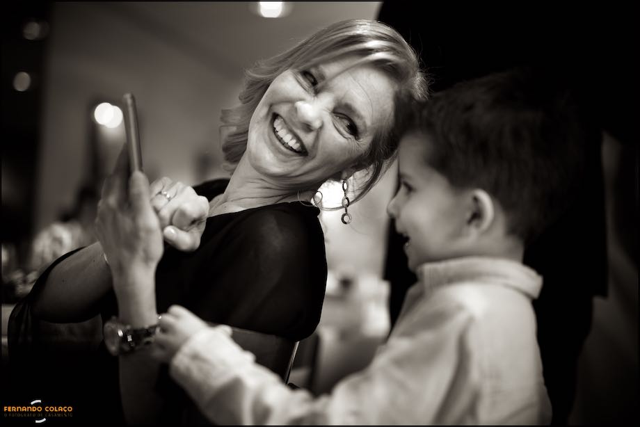 Groom's mother shows a photo on her cell phone to a boy.