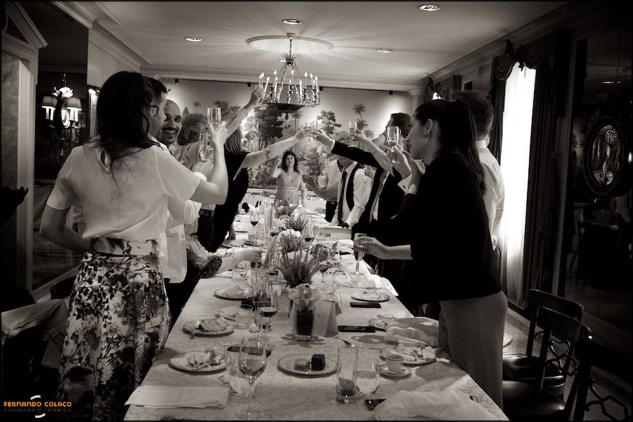 Guests, at the table and standing, make a toast to the bride and groom.