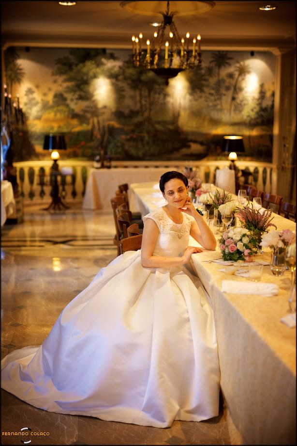 Bride, sitting at the table after the wedding party, poses for the wedding photographer.
