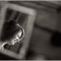 During the bride's preparation, the wedding photographer in the Algarve captures her face inside a mirror that was on a bed, creating a beautiful composition.