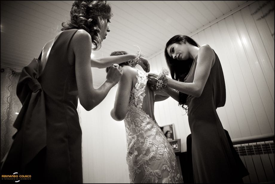 Irmãs acertando o vestido da noiva na preparação para a ida para a cerimónia, pelo fotógrafo de casamento na Guarda.