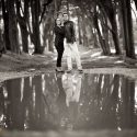 Numa estrada rodeada de árvores na Peninha em Sintra, o casal em frente de uma grande poça de água, com o seu reflexo, numa composição do fotógrafo de casamento.