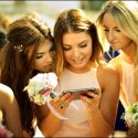 Amigas da noiva vendo fotografias num telemóvel depois da cerimónia, na Nazaré, pelo fotógrafo de casamento.