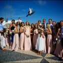 Pomba voando em frente de um grupo de convidados de um casamento a serem fotografados na Nazaré pelo fotógrafo de casamento..