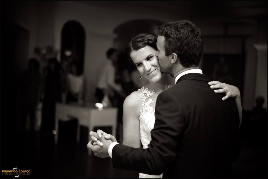 O casal, acabado de se casar, na sua primeira dança na festa, no momento em que o noivo beija a noiva na face, captados pelo fotógrafo de casamento em Lisboa.