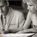 Noiva assina o documento do casamento junto do noivo, desfocado, vista pelo fotografo de casamento em Lisboa.
