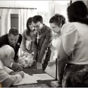 Noivos e padrinhos junto do padre que, sentado, assina os documentos oficiais do casamento, numa composição do fotógrafo de casamento no Alentejo.