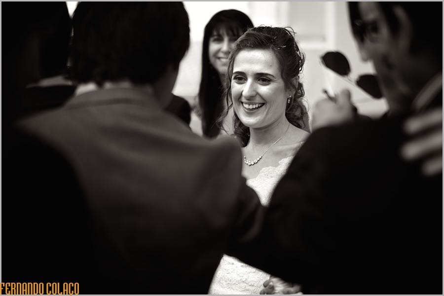A noiva sorri de felicidade entre convidados que a felicitam à saída da cerimónia do casamento.