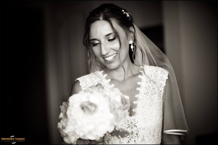 Com um sorriso feliz, a noiva olha para o bouquet que tem na mão, já de saída para a cerimónia do casamento na Basílica de Mafra onde o noivo a espera.