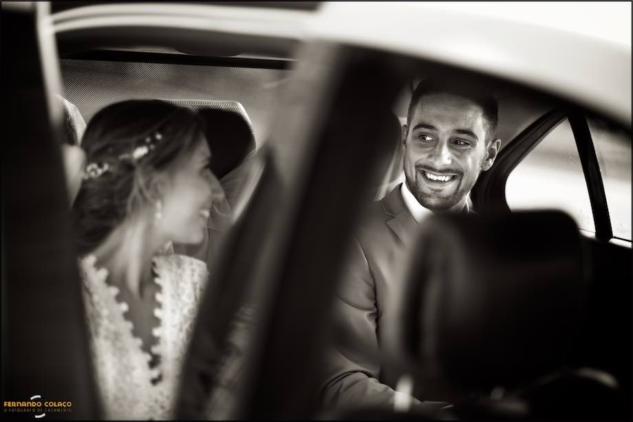 O noivo ri para a noiva quando entra dentro do automóvel que os vai levar para a festa do casamento.