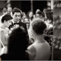 No meio dos convidados durante a cerimónia do casamento, os noivos, juntos, numa parte da liturgia, conforme o fotógrafo de casamento os viu.