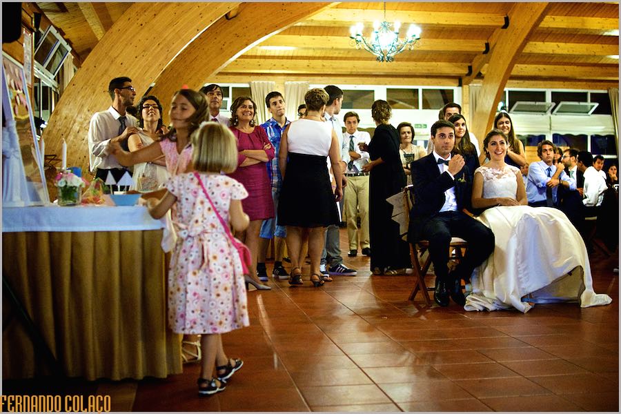 Os noivos, sentados à frente dos seus convidados, quando assistem a um vídeo sobre eles durante a festa do casamento na Quinta do Lumarinho.