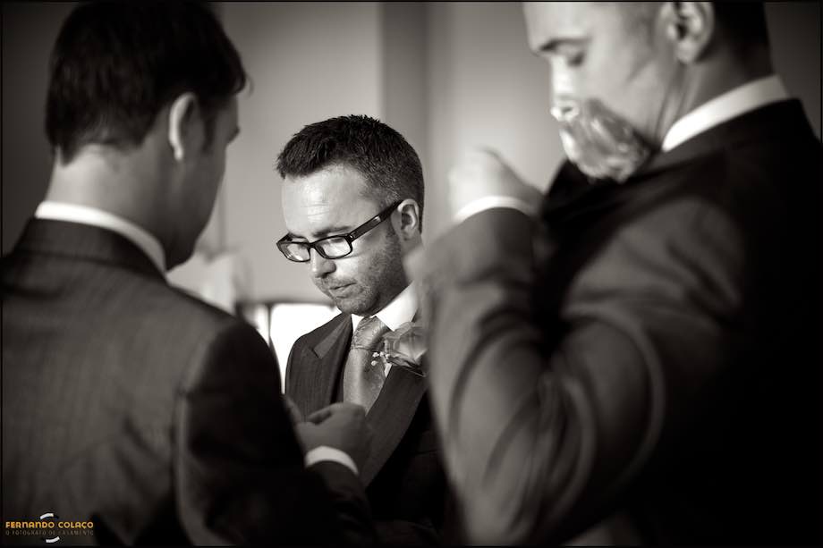 Friend of the groom being helped by him in the details of the coat and tie.