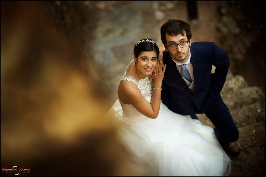 The couple, in the photo session, look up, in the stairs of the Alandroal castle, in a perspective of the wedding photographer in Portugal.