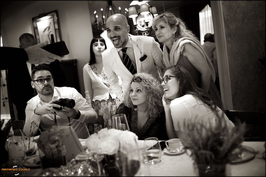 A group of guests at the table react to something during the wedding party.
