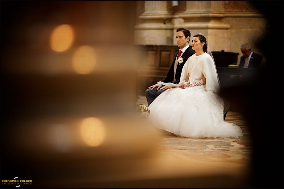 Bride and groom listening the priest during the homilia at Basílica de Mafra, in a composition of the wedding photographer in Lisbon.