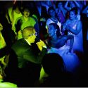 Under green and blue lights, the bride and groom dance among the guests during the wedding party at Casa de Reguengos.