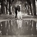 After a rain, the couple in a pre-wedding session, on a road flanked by large trees, in Peninha in Sintra, in front of a large puddle of water with its reflection, viewed by the Lisbon wedding photographer.