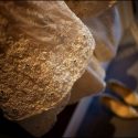 Detalhe do vestido da noiva com os sapatos ao fundo desfocados, com uma luz dourada, em composição pelo fotógrafo de casamento em Lisboa.