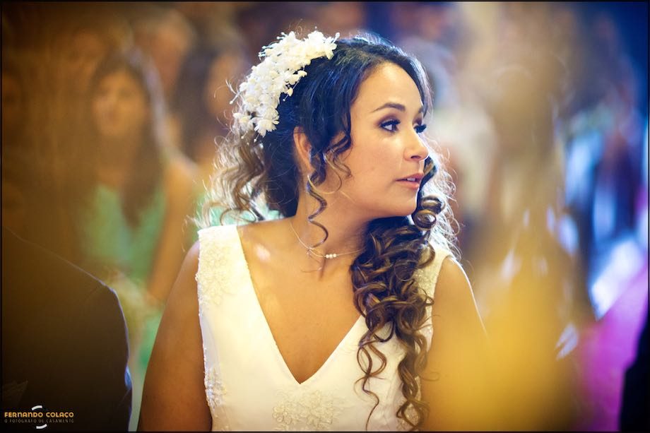 Noiva na cerimónia do casamento na igreja, banhada de luz dourada, conforme o fotógrafo de casamento a viu.