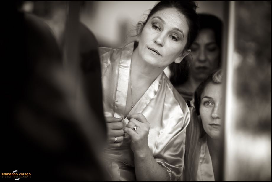 Mãe da noiva verifica se a maquilhagem lhe está bem, ao lado da filha.