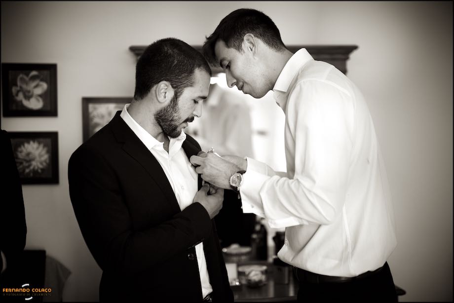 O noivo a ajudar um dos amigos a pôr uma flor no casaco, num momento capturado pelo fotógrafo de casamento.