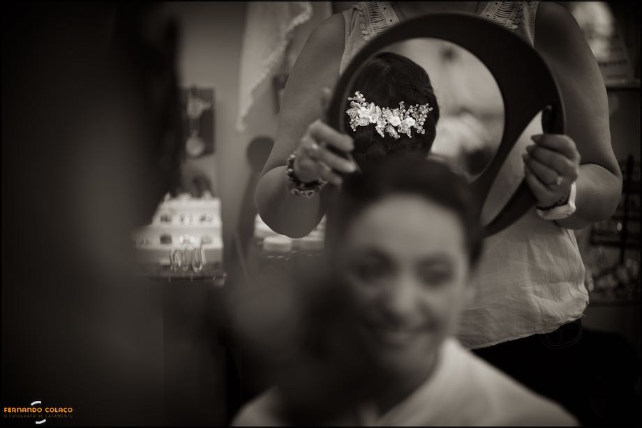 Flores no cabelo da noiva, visto no espelho na mão da cabeleireira.