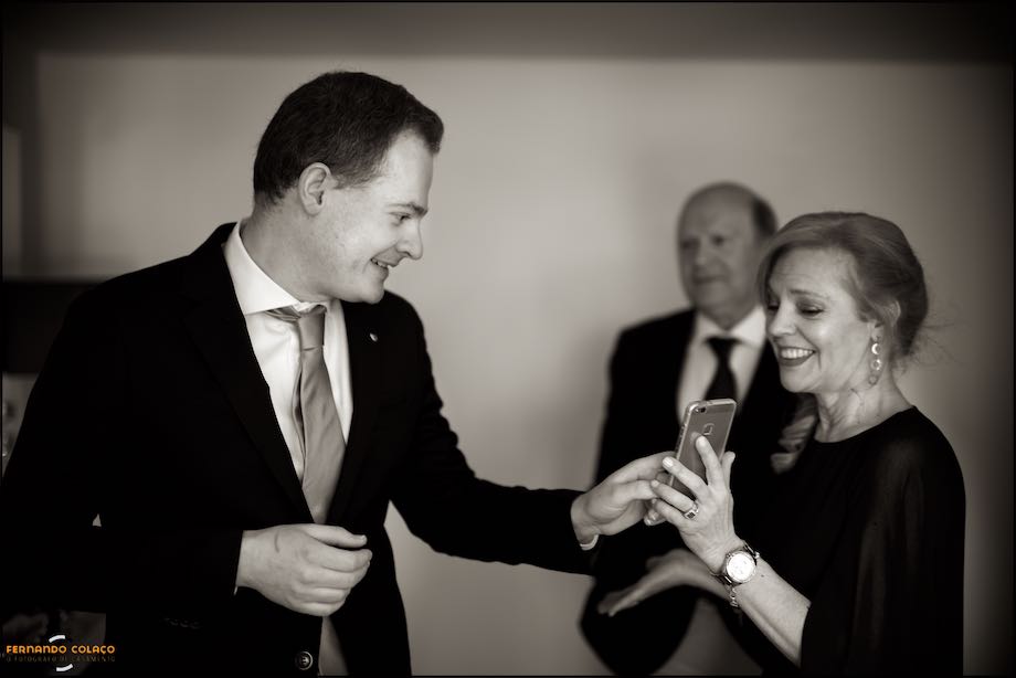 Mãe do noivo mostra-lhe uma fotografia no telemóvel.