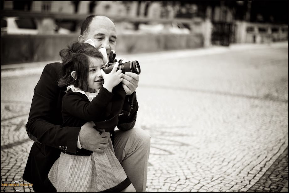 Pai ensina a sua pequena filha a fotografar.