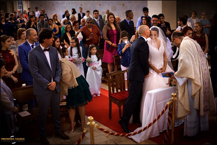 Groom kissing the bride near the altar, in a large view of the Church, bu the wedding photographer in Portugal.