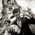 No final da saída da igreja, em fundo, o casal com ar feliz, num momento captado pelo fotógrafo de casamento.