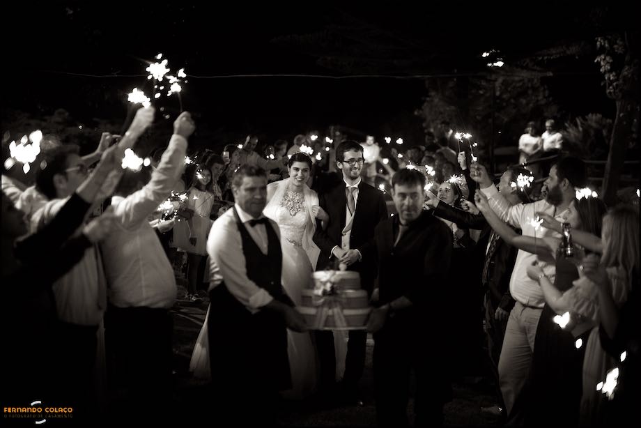 Com o bolo em frente, os noivos caminham por entre os convidados a acenar com luzes.