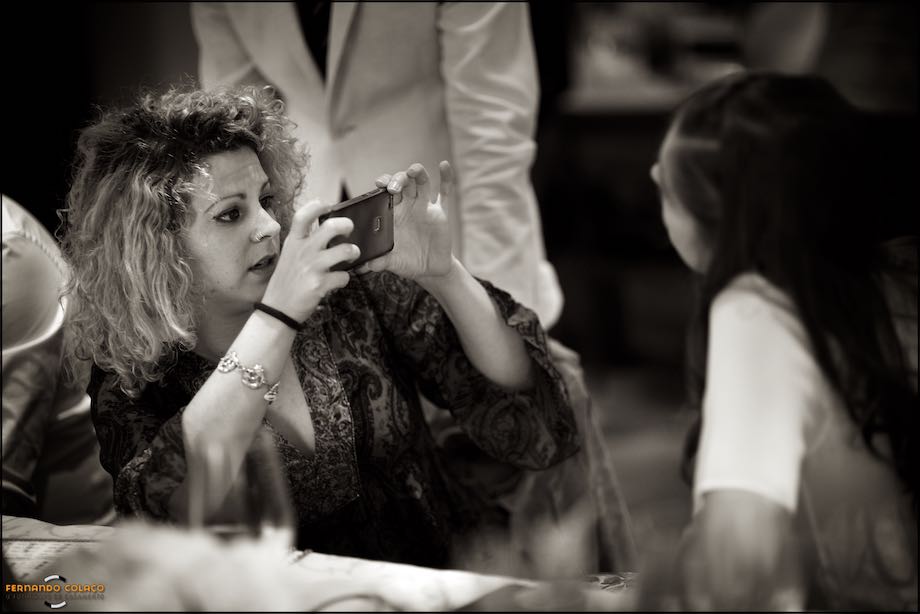 Uma convidada do casamento tira uma fotografia a outra com o telemóvel.