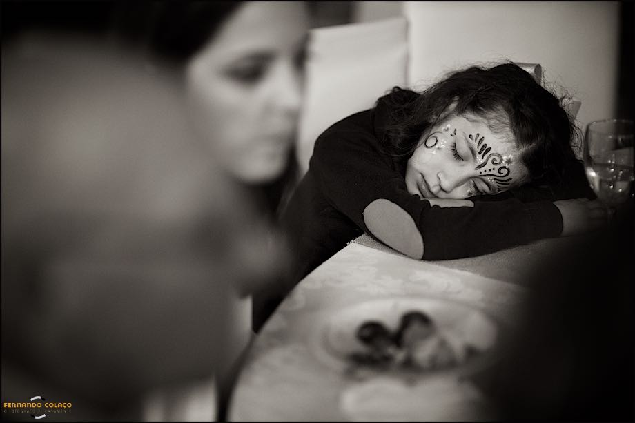 Menina com a cara decorada, a dormir sobre uma mesa na festa do casamento.