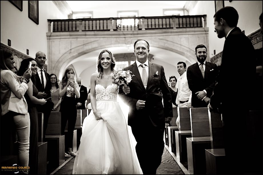 A noiva percorre a igreja com seu pai, entre os convidados.