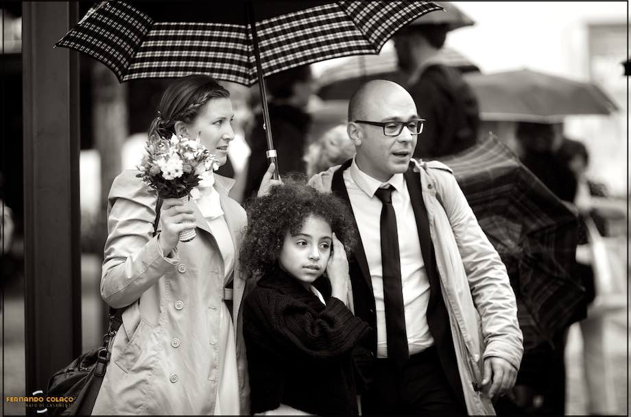 Os noivos com a sua filha, debaixo de um guarda chuva.