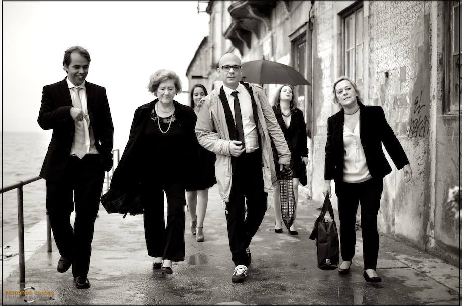 O noivo com a mãe, em frente de outros convidados, caminhando.