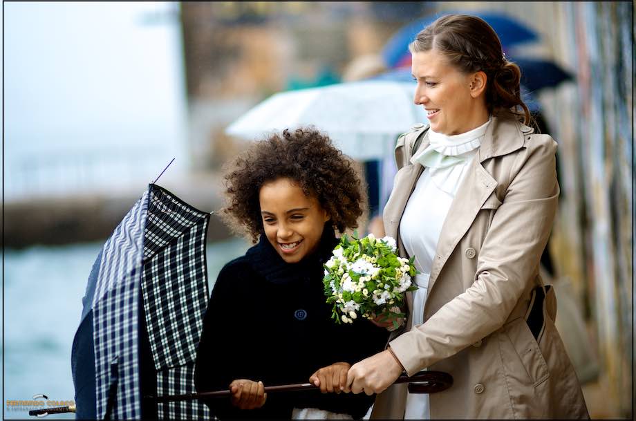 A noiva, com o bouquet na mão, com a filha fechando um guarda chuva.