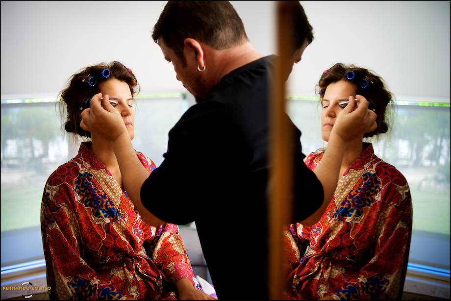 Noiva a ser maquilhada com a sua imagem reflectida num espelho.