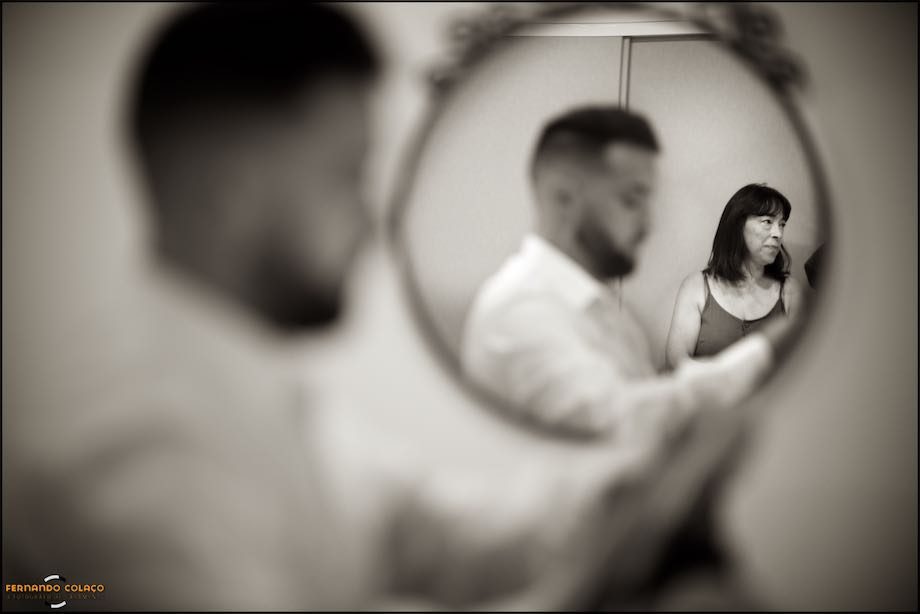 Mother of the groom, in a mirror, as her son prepares for the wedding.