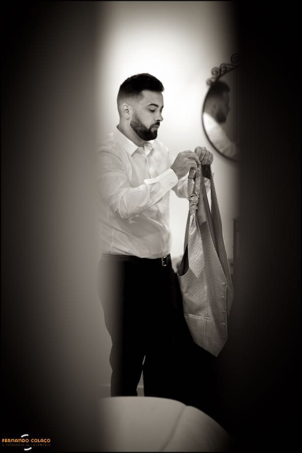 The groom preparing his tie and waistcoat.