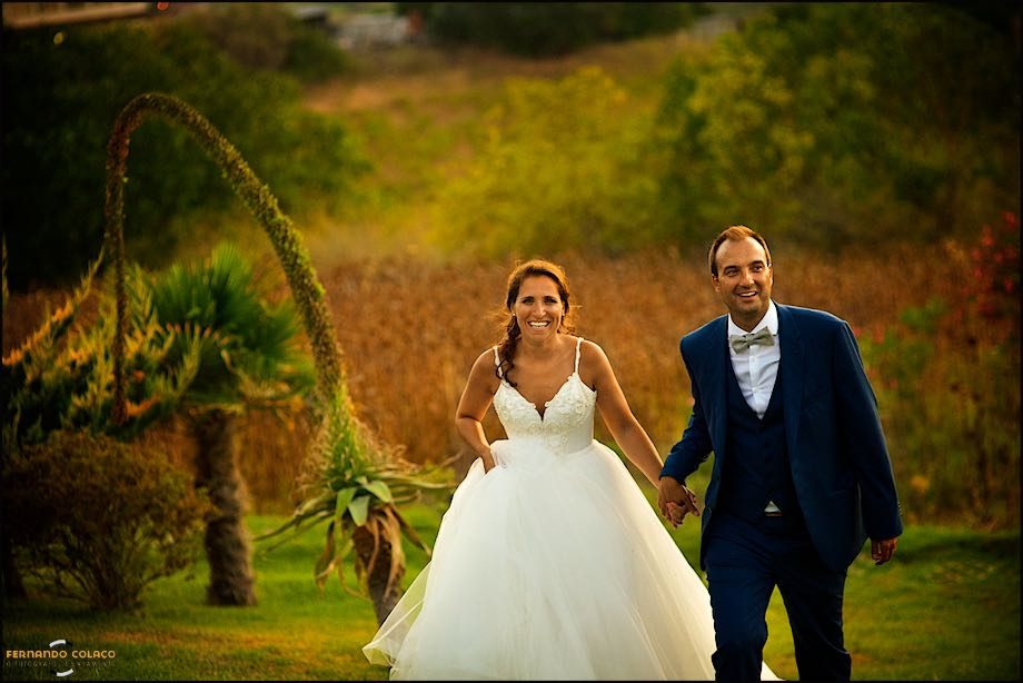 The newlywed couple walk up the hill at Quinta dos Pézinhos on the Tagus under golden light.