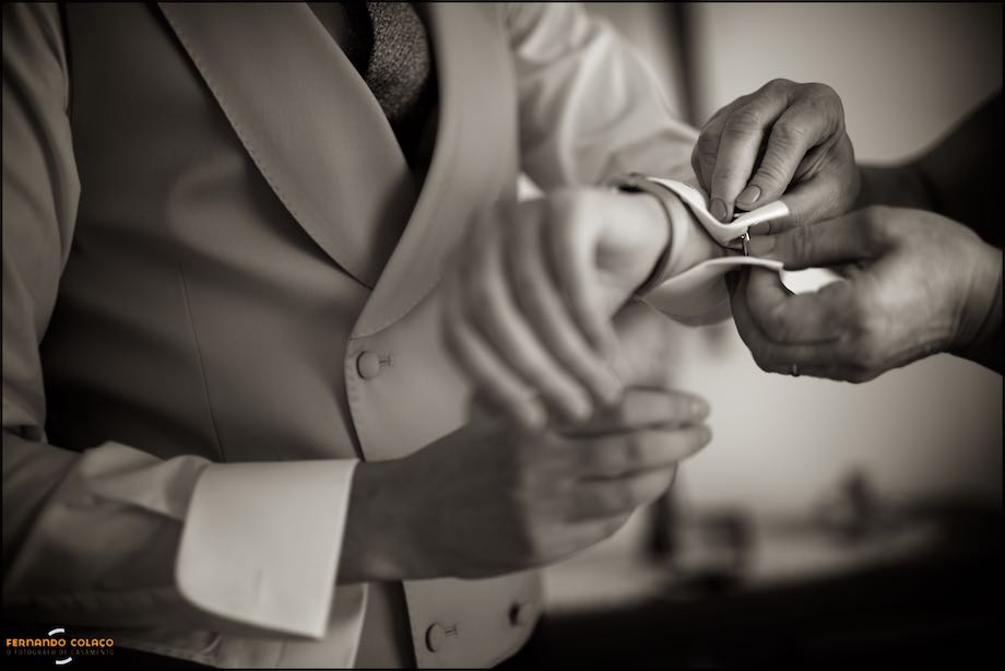 Hands button the cufflinks of the shirt, in the dress for the wedding, composed by the wedding photographer in Portugal.